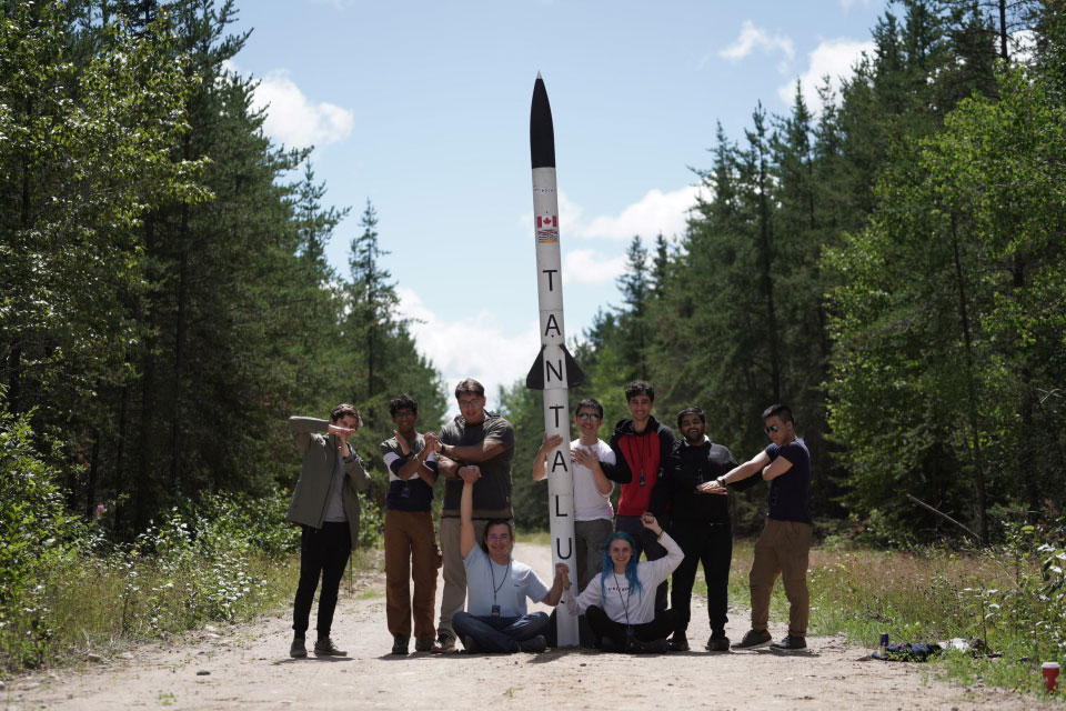 UBC Rocket team outdoors and in front of their rocket 