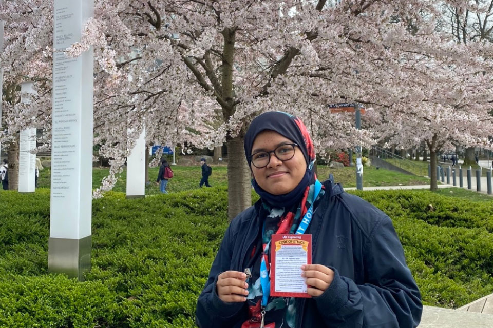 Jasia Azreen shows her Iron Pin outside with a cherry blossom tree in the background