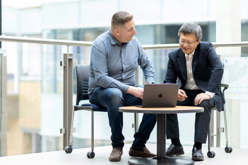Jozsef Hamari and Dr. Zheng Liu sitting together and staring at a laptop