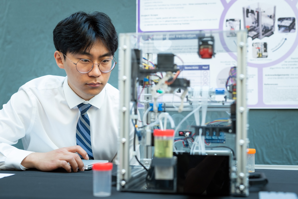 A student observes the RapidAST device, which holds a liquid sample in a small container. 