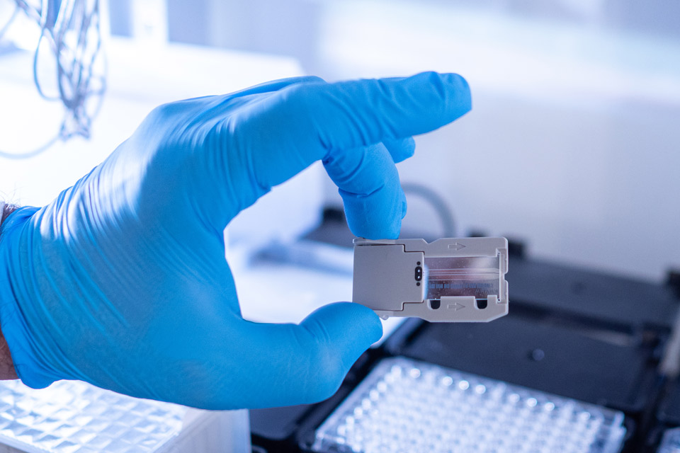A man holds an Erlenmeyer flask of green liquid