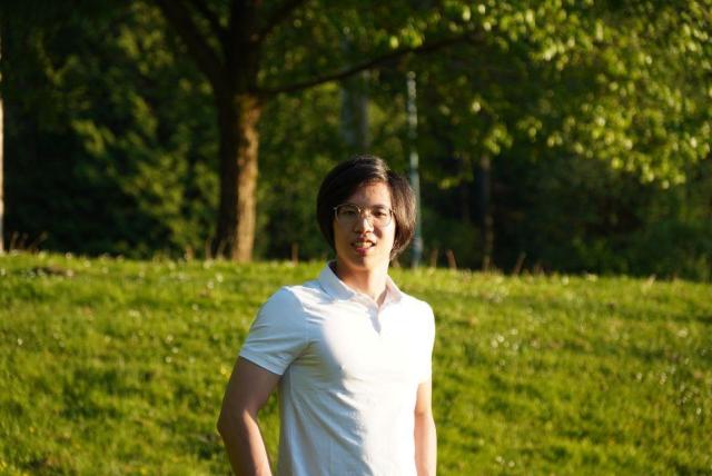Image of Yi Yi Du wearing a white shirt and standing in grass