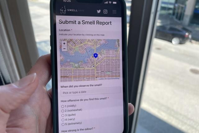 Phone screen with Smell Vancouver app open showing a map of Metro Vancouver and questions about users' experience of pollution