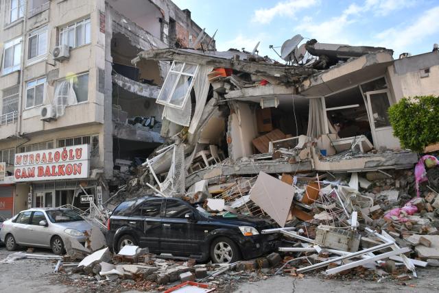 Rubble falling from collapsed building onto a black car as a result of an earthquake