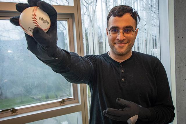 A person testing the smart glove and holding a baseball in his hand