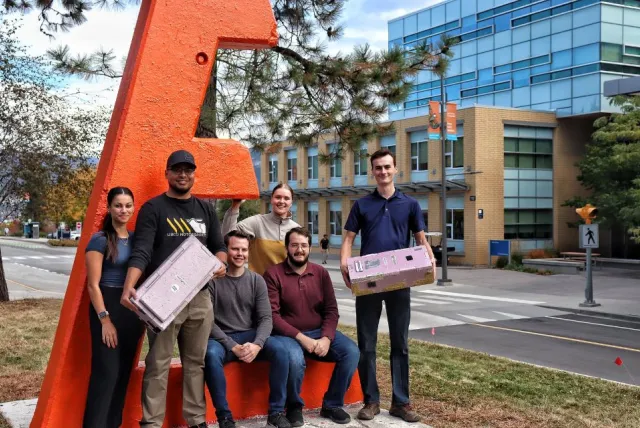 A UBC engineering Capstone team holds their project.