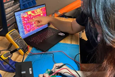 AeroDesign team members testing a circuit board while looking at a laptop. 