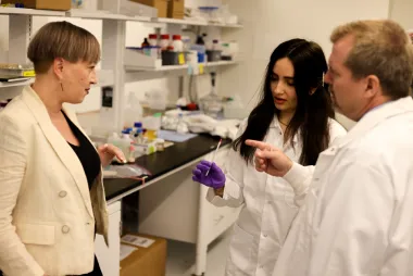 The Spikeless team in a lab, from left to right: Sasha Santos, Samin Yousefi, and Dr. Johan Foster. Santos and Foster are standing on either side of Yousefi, who is holding a stir stick with a pink tip.