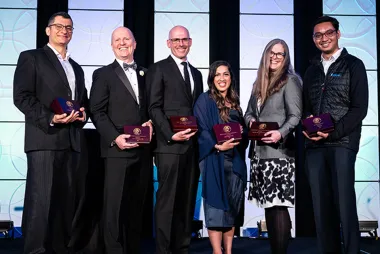 Recipients of Engineers Canada Awards stand on stage holding their award plaques