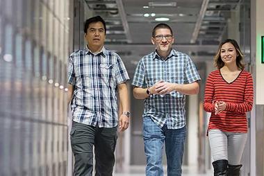 Two students and a professor walking down a hallway