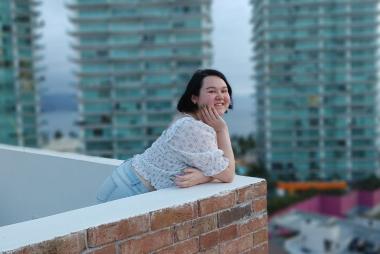 UBC CHBE student Jessica Yamamoto smiles at the camera while leaning on a ledge. She is centred with buildings behind her.