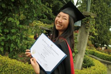 Bev Ng, Bachelor of Civil Engineering graduate smiles for the camera in her graduation cap and gown while holding her degree.