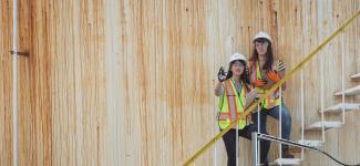 Two students standing in an outdoor stairwell observing the project site.