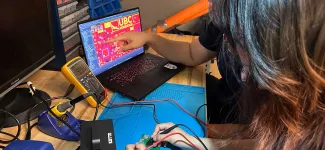 AeroDesign team members testing a circuit board while looking at a laptop.