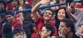 Students smile and wave in a crowd 