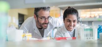 A male research supervisor with a female graduate student in a lab setting.