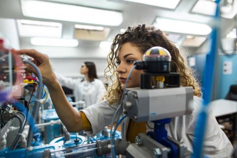 Two women in a lab inspecting wiring on electrical equipment