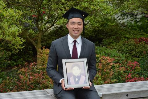 UBC Engineering student Tyler Lum poses in his graduation cap while holding a photo of his late uncle.