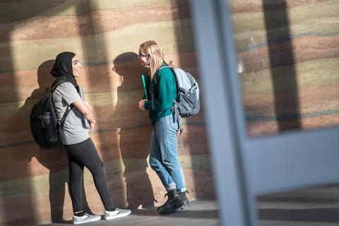 Two students standing against a wall at UBC Okanagan