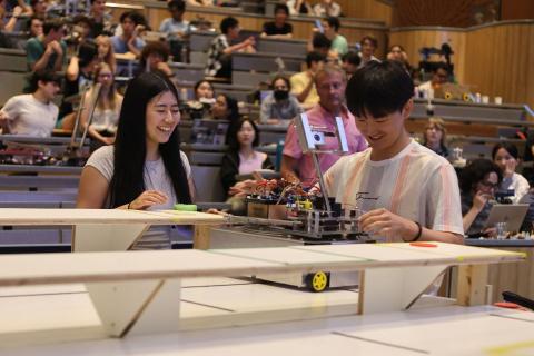 Two students smile while preparing their robot.