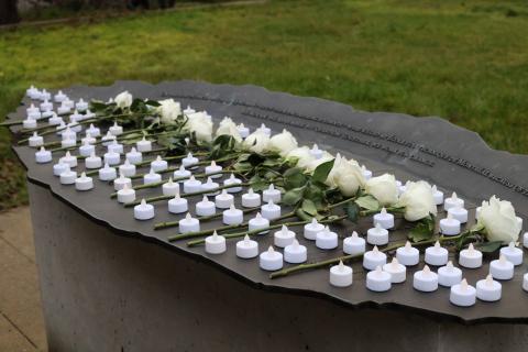 A memorial that is covered in white roses and candles.