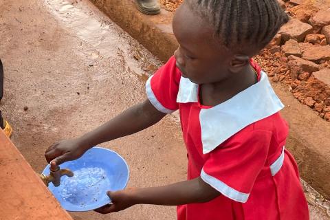 A child fills a bowl with clean water.