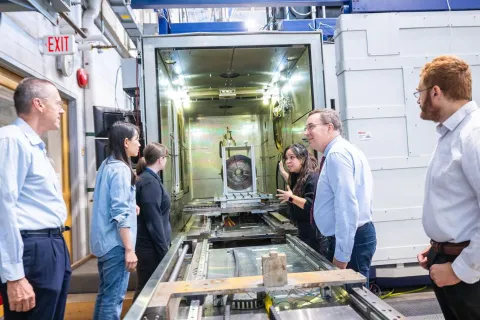 A group of people look at an electron beam manufacturing platform