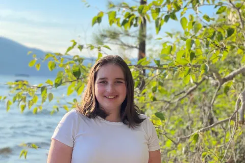 Janelle smiling in front of trees and ocean