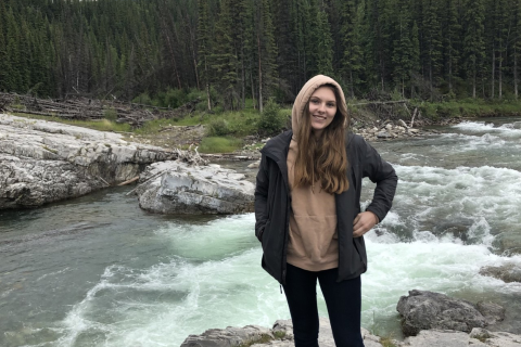 Katrijn, standing in front of a river, smiling