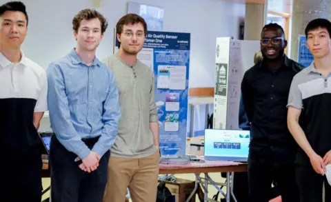 IoT ECE team standing around their presentation.