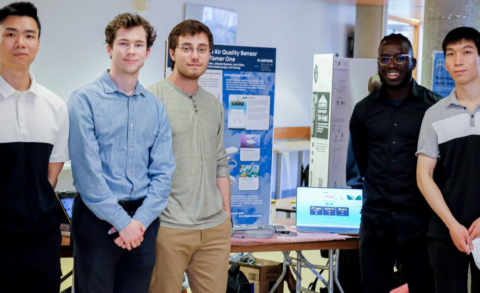 IoT ECE team standing around their presentation. 