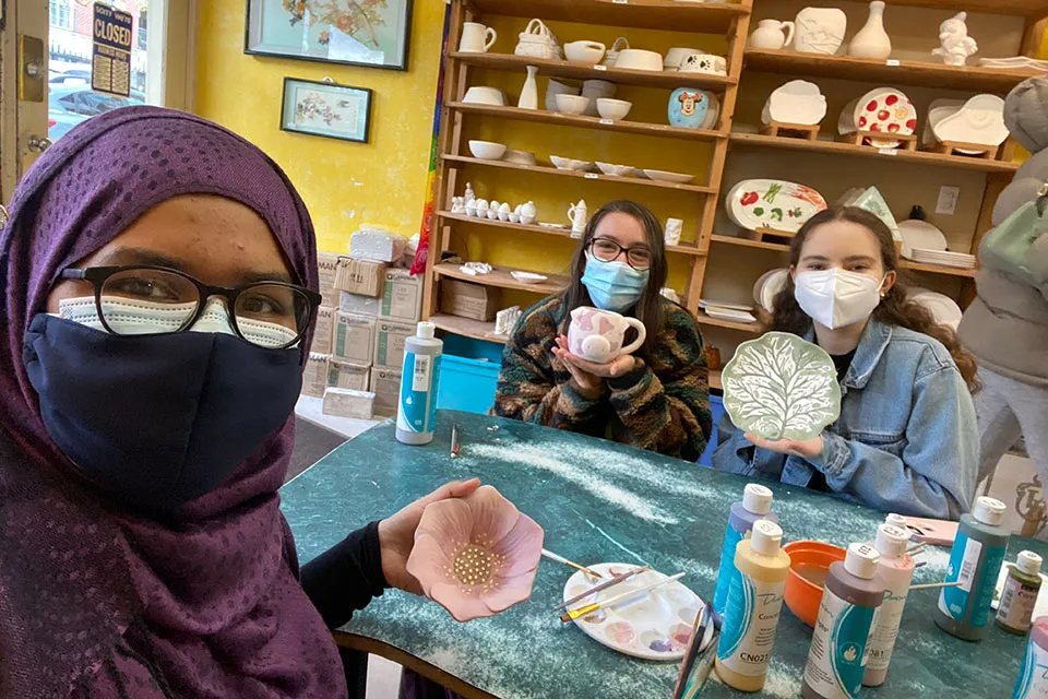 Jasia with friends displaying their pottery creations
