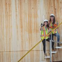 Two students standing in an outdoor stairwell observing the project site.